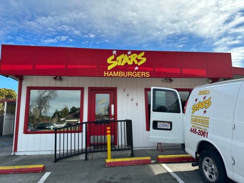 A red and white building with a sign reading "Stars Hamburgers" and a delivery van parked outside.