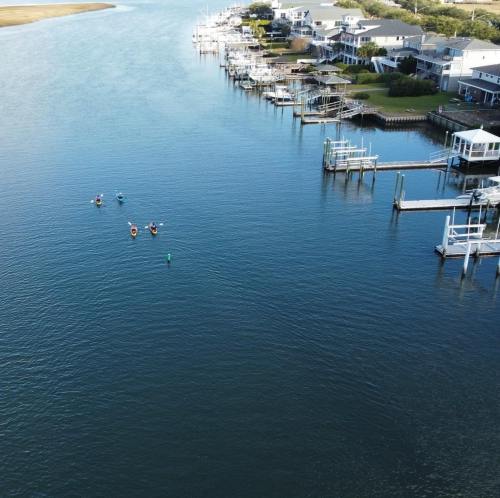 Aerial view of a calm waterway with kayakers and waterfront homes along the shore.