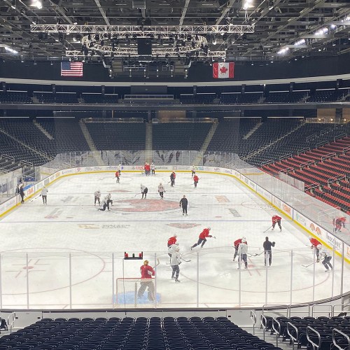 A hockey practice session on an ice rink, with players in jerseys and empty stands in a modern arena.
