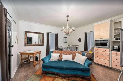 Cozy living room with a blue sofa, wooden furniture, and a chandelier, featuring a warm, inviting atmosphere.