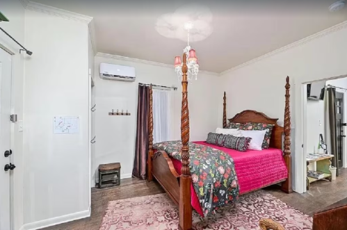 Cozy bedroom featuring a four-poster bed with pink bedding, a chandelier, and warm wooden accents.