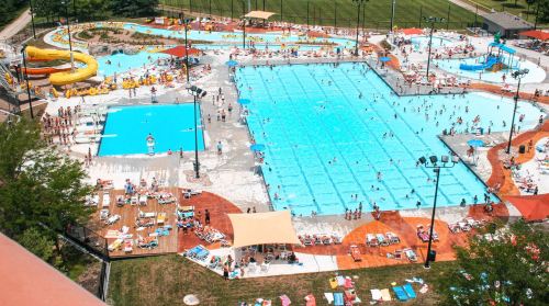 Aerial view of a busy water park with multiple pools, slides, and sunbathers enjoying a sunny day.