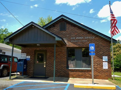 A brick building with a sign reading "U.S. Post Office" and an American flag, located in Waverly, AL.