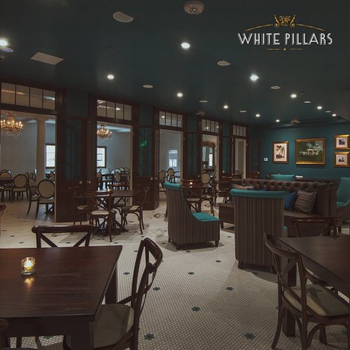 Elegant dining room with teal walls, chandeliers, and stylish furniture, creating a cozy atmosphere.