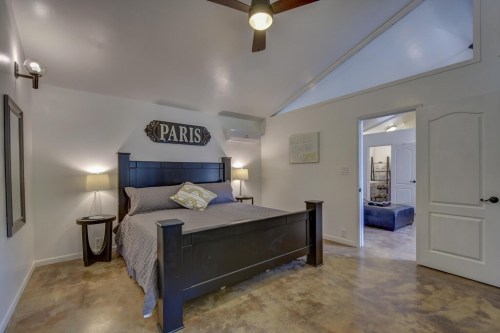 Cozy bedroom with a black bed, Paris sign, and modern decor; features a ceiling fan and light-colored walls.