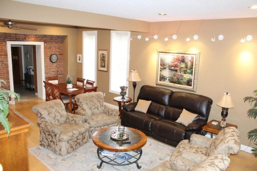 Cozy living room with a leather sofa, armchairs, a round coffee table, and a dining area in the background.