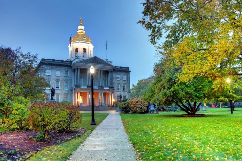 A historic building with a golden dome, surrounded by colorful trees and a pathway, under a twilight sky.
