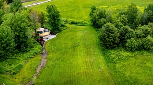 Aerial view of a lush green field with a circular patio and trees along the edges.