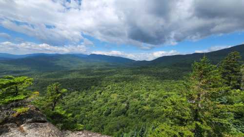 A panoramic view of lush green mountains under a partly cloudy sky.