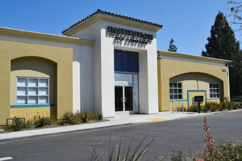 Exterior view of a building labeled "Institution" with a modern design and landscaped surroundings.