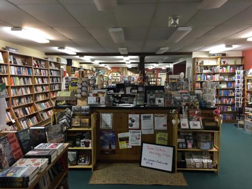A cozy bookstore interior with shelves of books, a wooden counter, and various displays throughout the space.