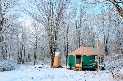 A cozy yurt surrounded by snow-covered trees in a winter landscape.