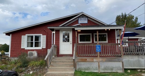 A red wooden building with a sign reading "Main Street Coffee House," featuring a porch and accessible entrance.