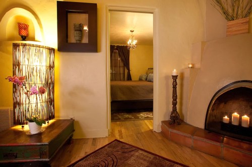 Cozy interior with warm lighting, a decorative lamp, candles, and a view into a bedroom through an open door.