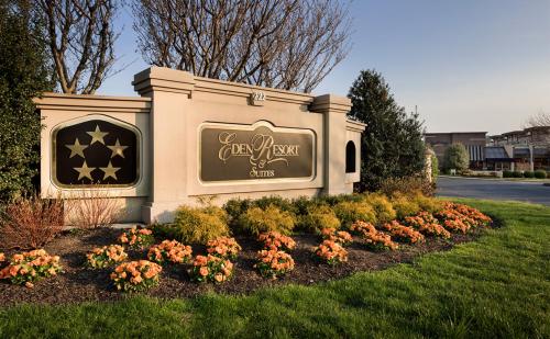 Sign for Eden Resort & Suites, surrounded by colorful flowers and greenery, with a clear blue sky in the background.