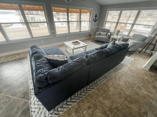 Cozy living space with a navy blue sectional sofa, a white coffee table, and large windows overlooking a scenic view.