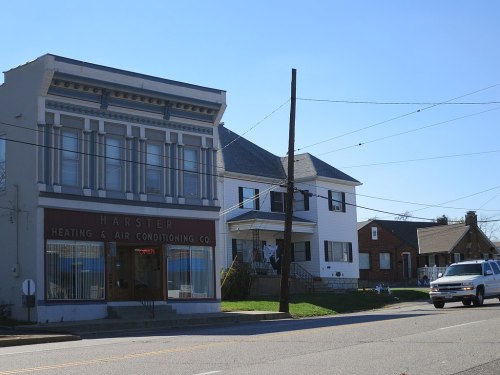 A street view featuring a heating and air conditioning company and residential homes under a clear blue sky.
