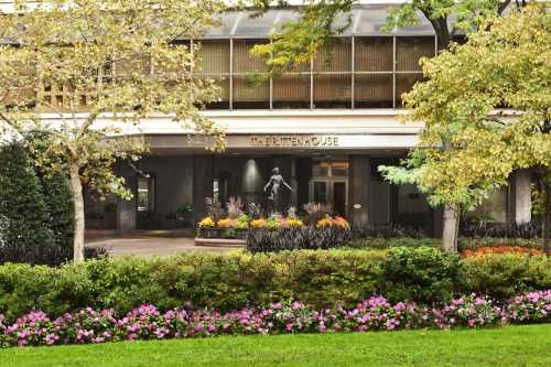 Entrance of a building with a statue, surrounded by colorful flowers and greenery.