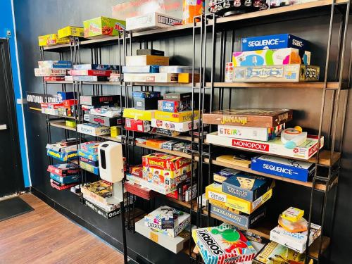 A wall-mounted shelf filled with various board games in colorful boxes, set against a dark blue background.