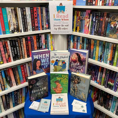 A display of books on a table with a sign that reads "I Read Them When," surrounded by shelves of more books.