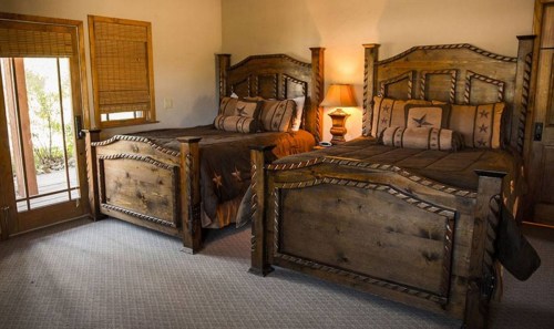 Cozy bedroom featuring two wooden beds with star designs, warm lighting, and a door leading to an outdoor area.