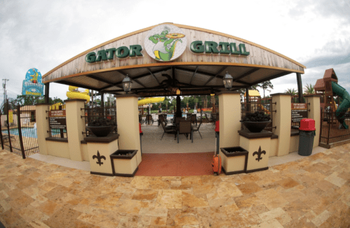 Entrance to Gator Grill, featuring a covered patio and pool area in the background, with colorful attractions visible.