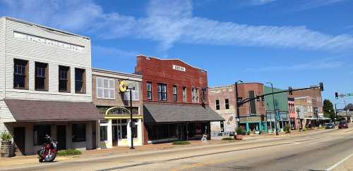 A sunny street view of a small town with historic buildings, shops, and a clear blue sky.