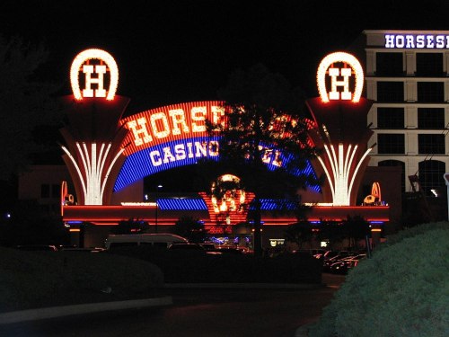 Brightly lit entrance of Horseshoe Casino at night, featuring colorful neon lights and a large sign.