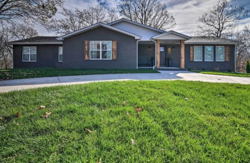A modern single-story home with a landscaped front yard and a concrete driveway under a cloudy sky.