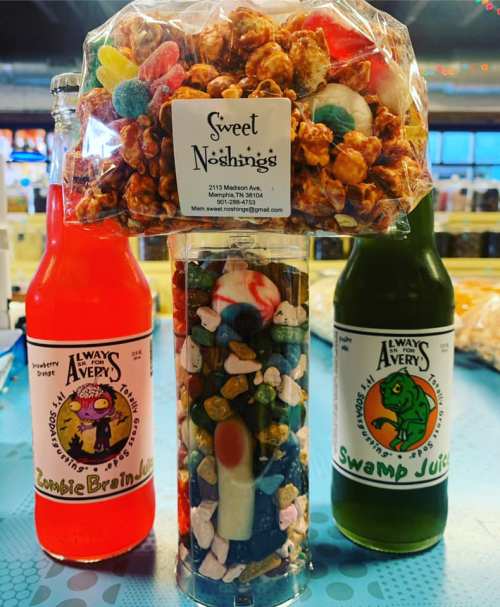 A colorful display of candy, popcorn, and two bottles of soda labeled "Zombie Brain Juice" and "Swamp Juice."