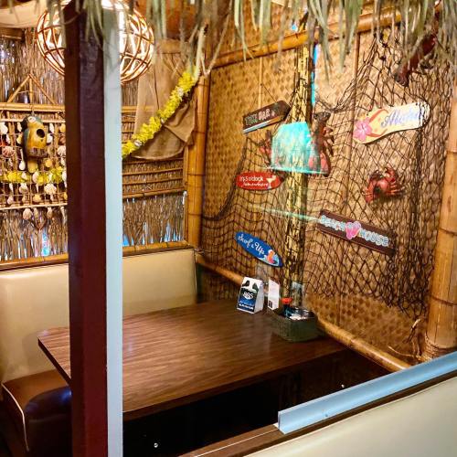 Cozy restaurant booth with bamboo decor, tropical signs, and a warm, inviting atmosphere.