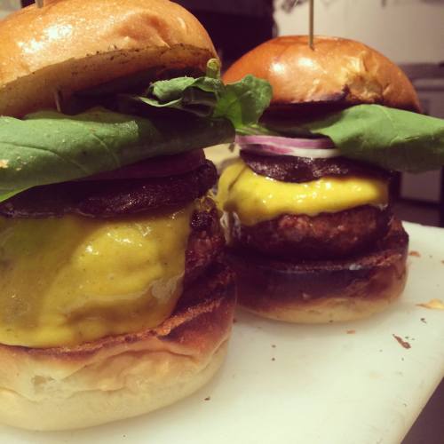 Two delicious cheeseburgers stacked with lettuce, onion, and melted cheese on toasted buns.