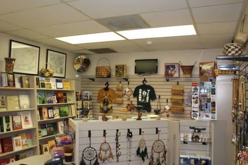 A cozy shop interior featuring shelves of books, crafts, and decorative items, with baskets and wall art displayed.