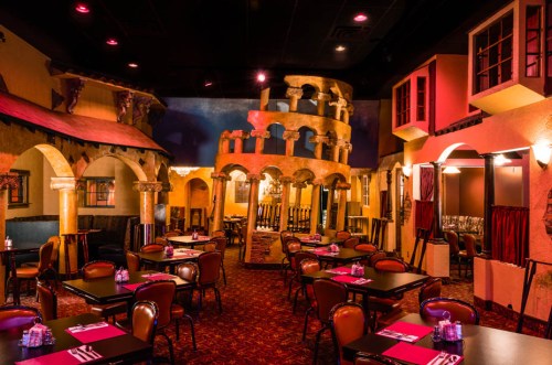 Interior of a vibrant restaurant featuring colorful walls, decorative architecture, and tables set for dining.
