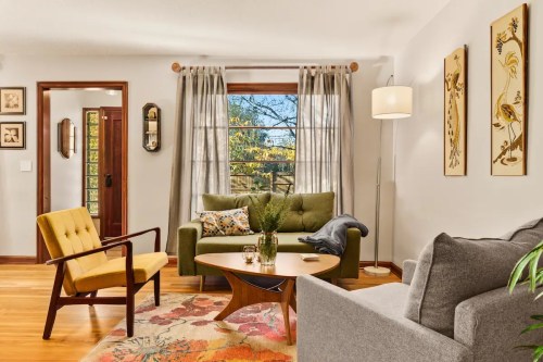 Cozy living room with green and gray sofas, a wooden coffee table, and large windows letting in natural light.