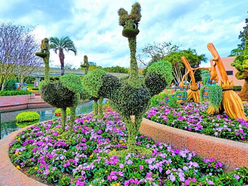 Topiary sculptures of ostriches surrounded by colorful flowers in a landscaped garden.