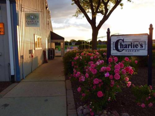 Exterior view of Charlie's Restaurant, featuring a sign and blooming pink roses along the pathway.