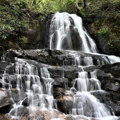 A serene waterfall cascading over rocky terrain, surrounded by lush greenery.