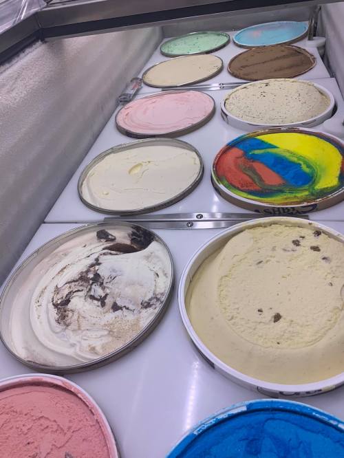 A variety of ice cream tubs in different colors and flavors displayed in a freezer.