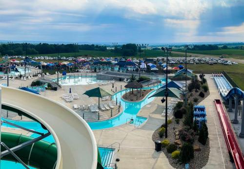 Aerial view of a water park with slides, pools, and a large crowd under colorful umbrellas in the background.