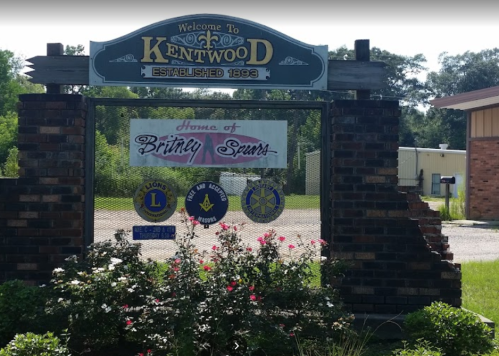 Welcome sign for Kentwood, established 1896, featuring a banner for Britney Spears and local organizations.