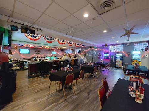 A spacious restaurant interior with tables, a bar area, and festive decorations, including red, white, and blue bunting.
