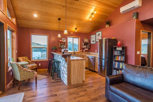 Cozy interior of a modern cabin with a kitchen, living area, and large windows showcasing mountain views.