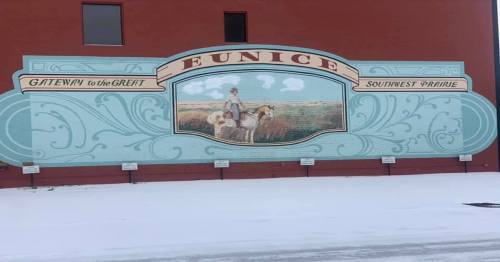 Mural on a red building featuring a cowboy on horseback, with text "Eunice: Gateway to the Great Southwest Prairie."