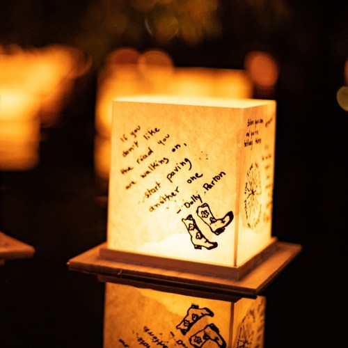 A glowing lantern with handwritten text reflecting on connection and understanding, floating on water at night.