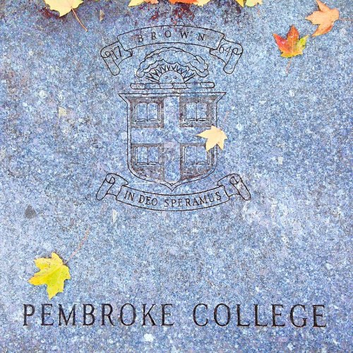 Engraved stone with "Pembroke College" and a crest, surrounded by autumn leaves.