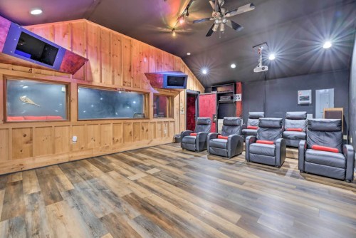Home theater room with reclining chairs, wooden walls, and a projector, featuring a cozy, modern design.