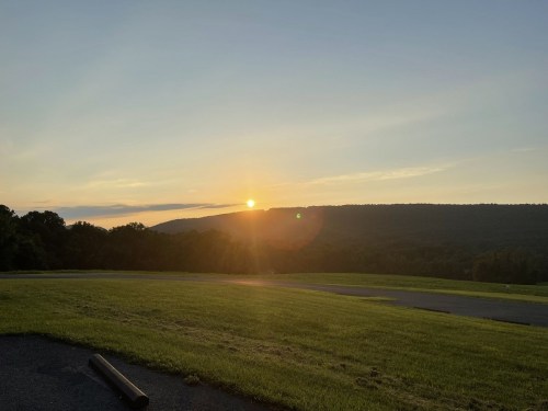 A serene sunset over rolling hills, with a clear sky and vibrant colors illuminating the landscape.