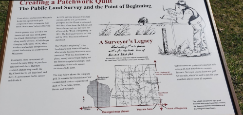 Sign explaining the Public Land Survey and the Point of Beginning, featuring a map and illustration of a surveyor.