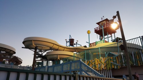 Water park slides and play structures under a clear sky, with a light post illuminating the scene.